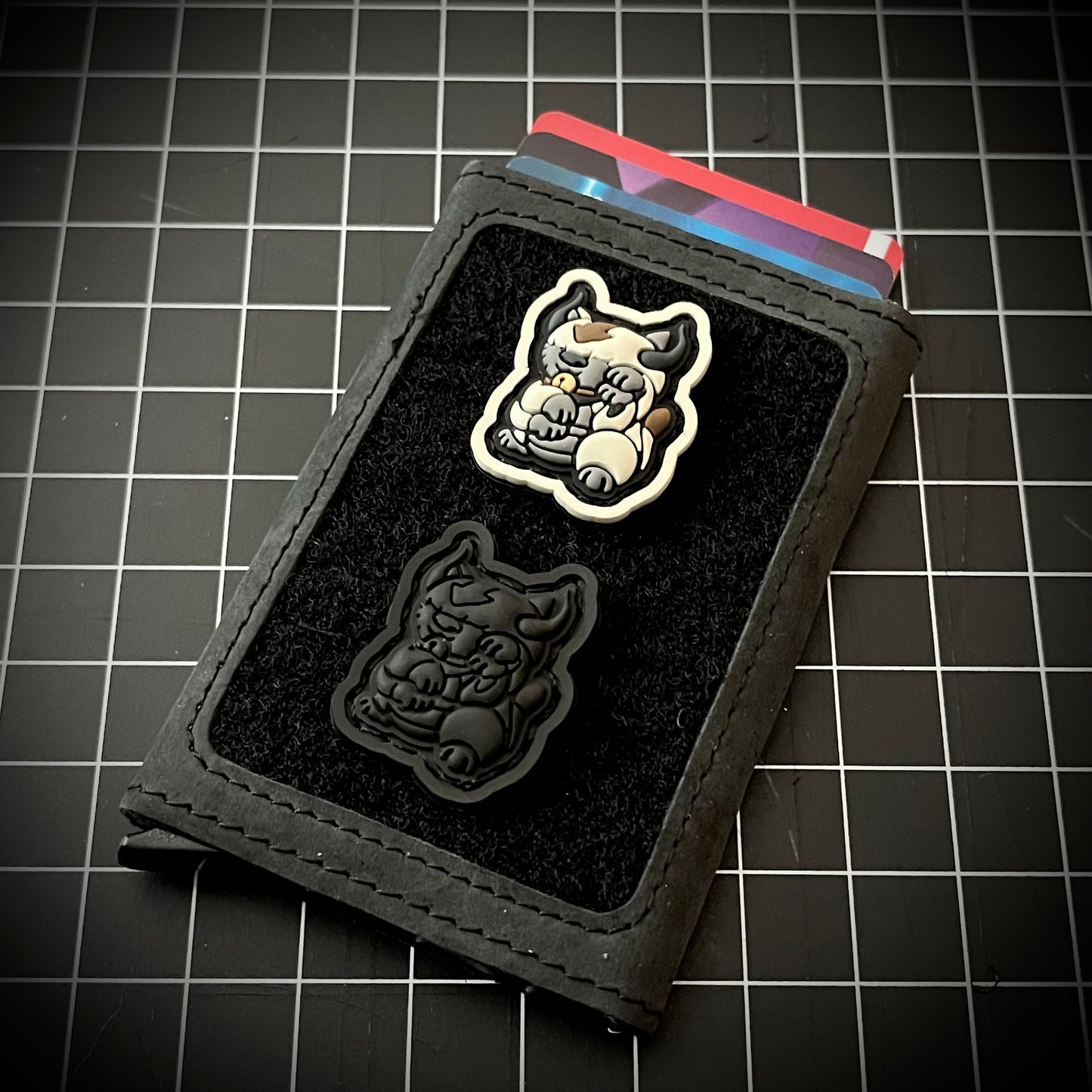 Appa Neko RE and Appa Neko Blackout RE of a bison sitting in a lucky cat maneko pose on a velcro wallet with a grid background.