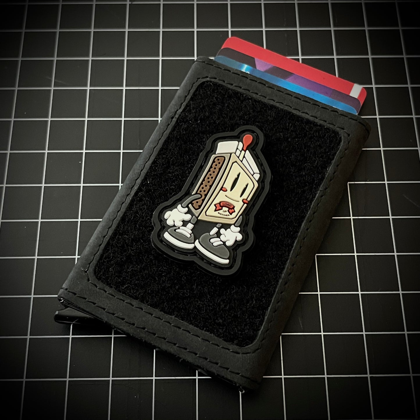 Matchbox RE on a velcro wallet and grid background.