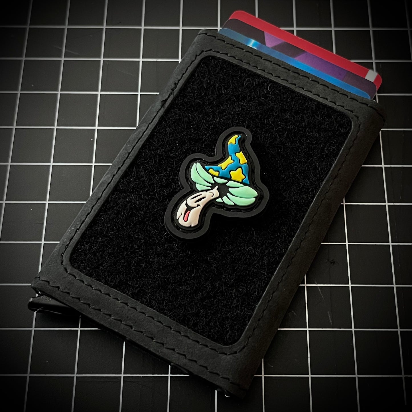 Shroomie RE PVC ranger eye morale patch of a green and yellow mushroom character on a velcro wallet and grid background.