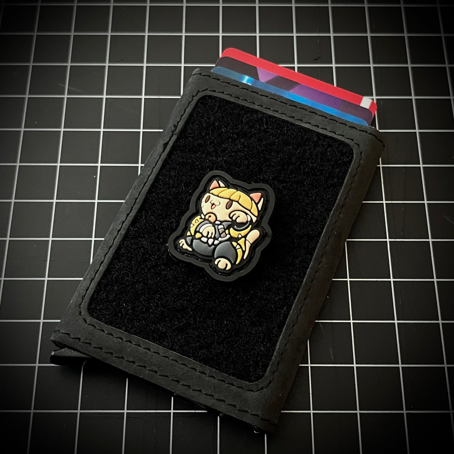 Thunder Swordsman Neko RE PVC ranger eye morale patch of a blond anime character in a lucky cat maneki-neko pose on a wallet and grid background.