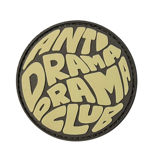Anti Drama Drama Club RE PVC ranger eye morale patch - A circle round patch that says Anti Drama Drama Club. Primary color is green beige.