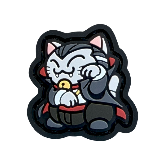 Dracula Neko RE Halloween ranger eye velcro patch depicting a cat dressed as a vampire with pointy teeth in a maneko lucky cat pose.