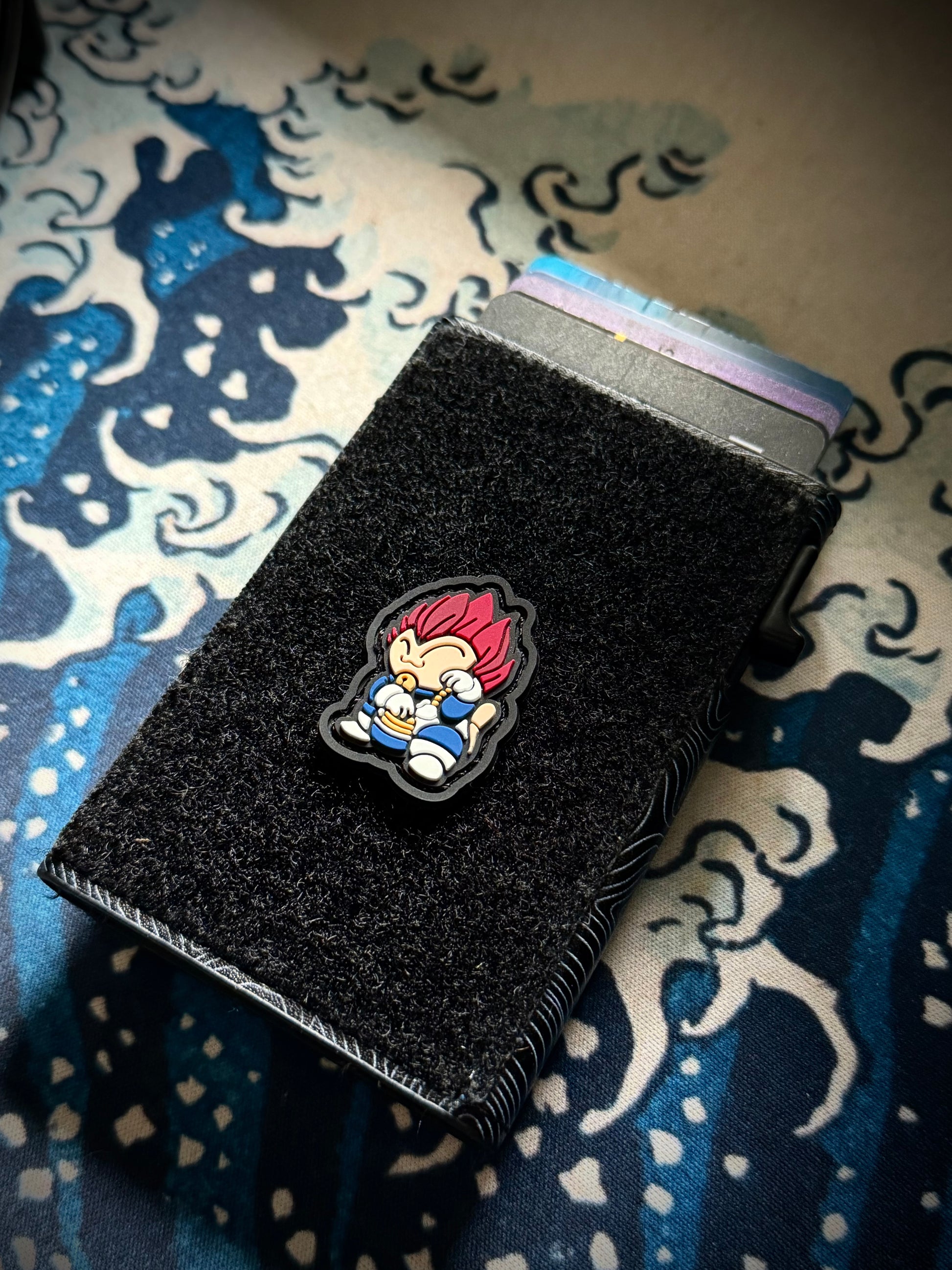 Galactic-Prince Neko RE ranger eye pvc morale patch Character with red hair and blue outfit in a lucky cat maneko pose on a velcro wallet with a Great Wave background.