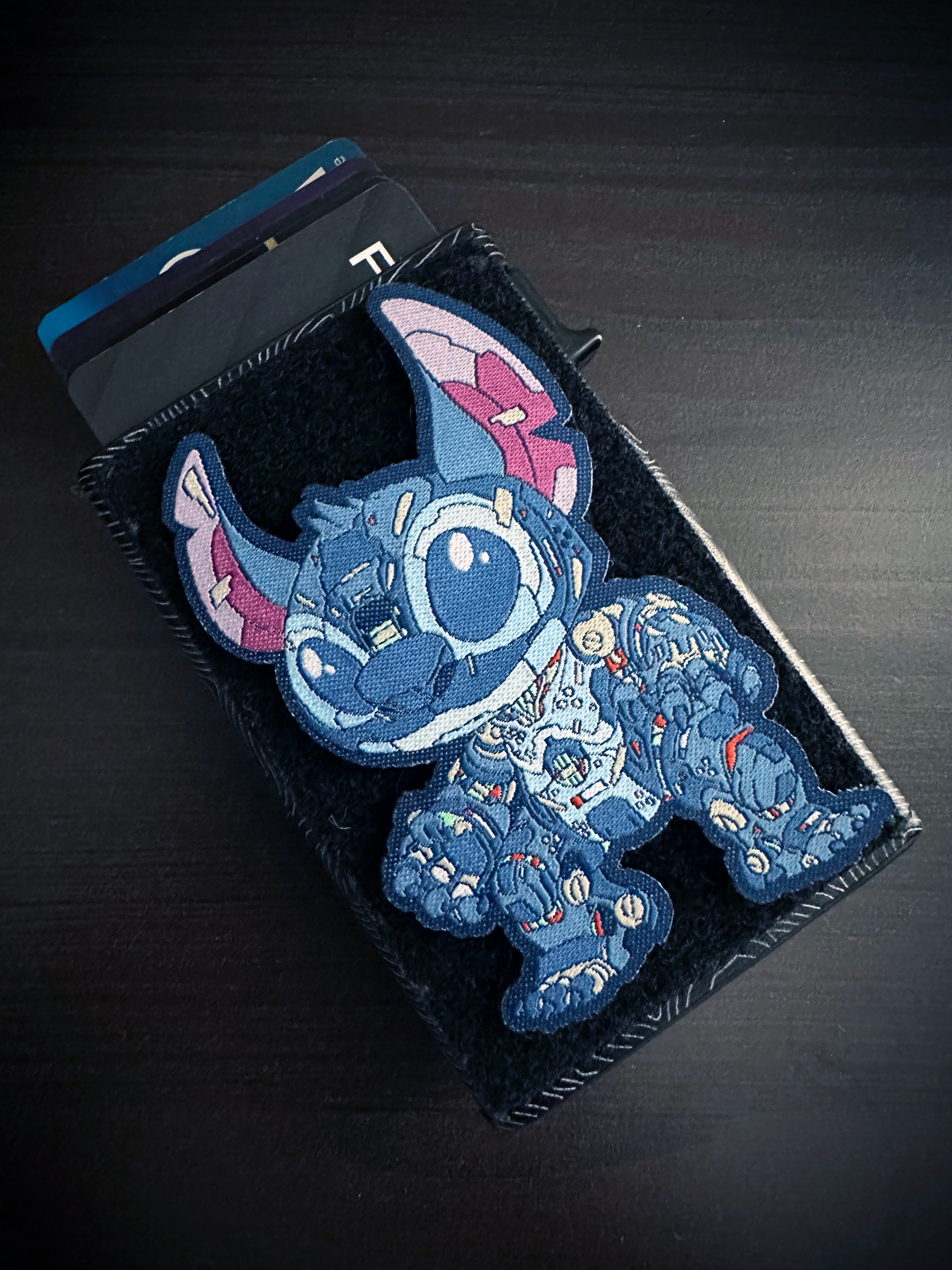 Mechasoul Stitch Patch Blue cartoon character patch on a black wallet with a dark background