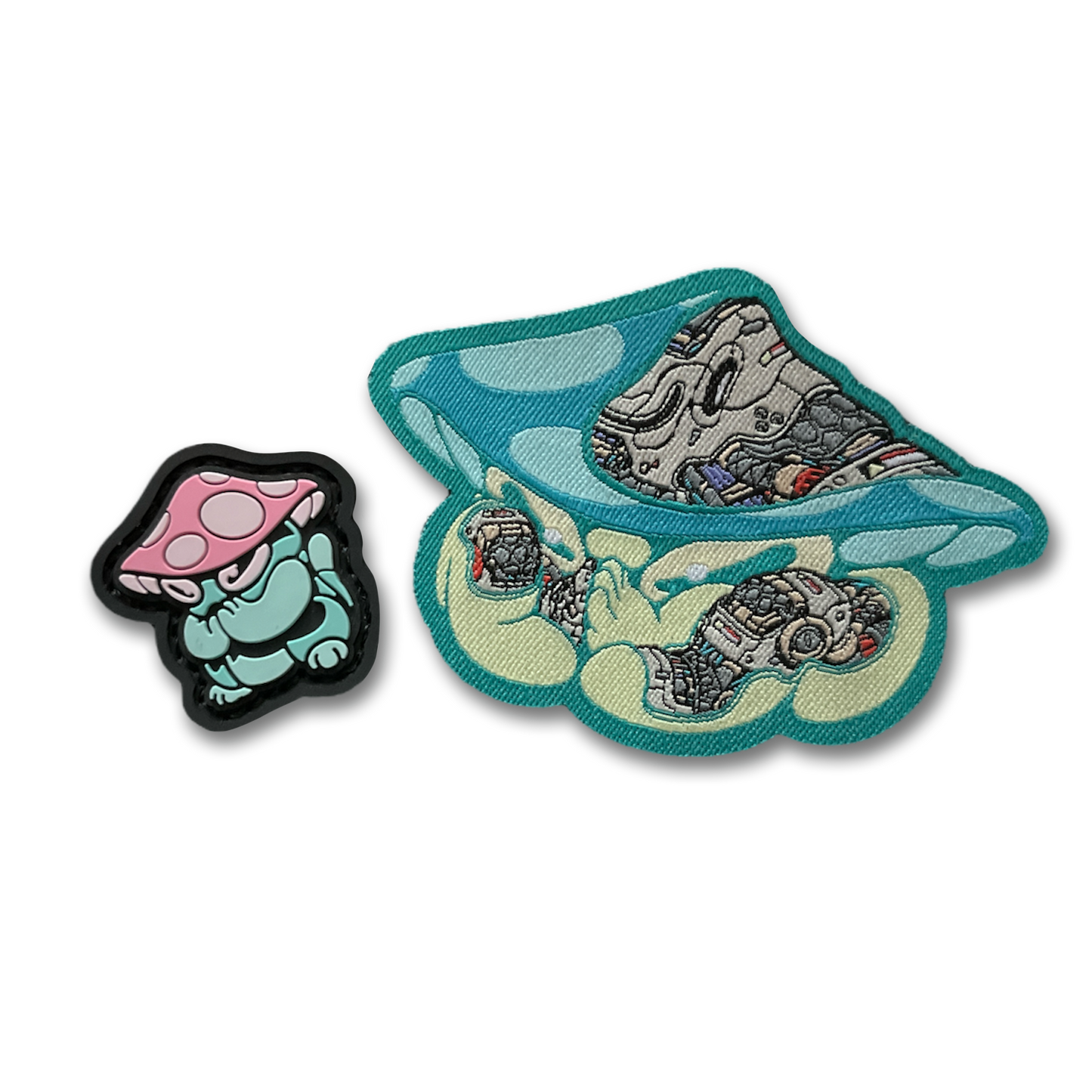 Praying Mushroom Patch Set depicting 2D PVC patch of a green mushroom character with pink and white cap in a lucky cat maneko pose and a woven nylon mechanical style green mushroom patch.