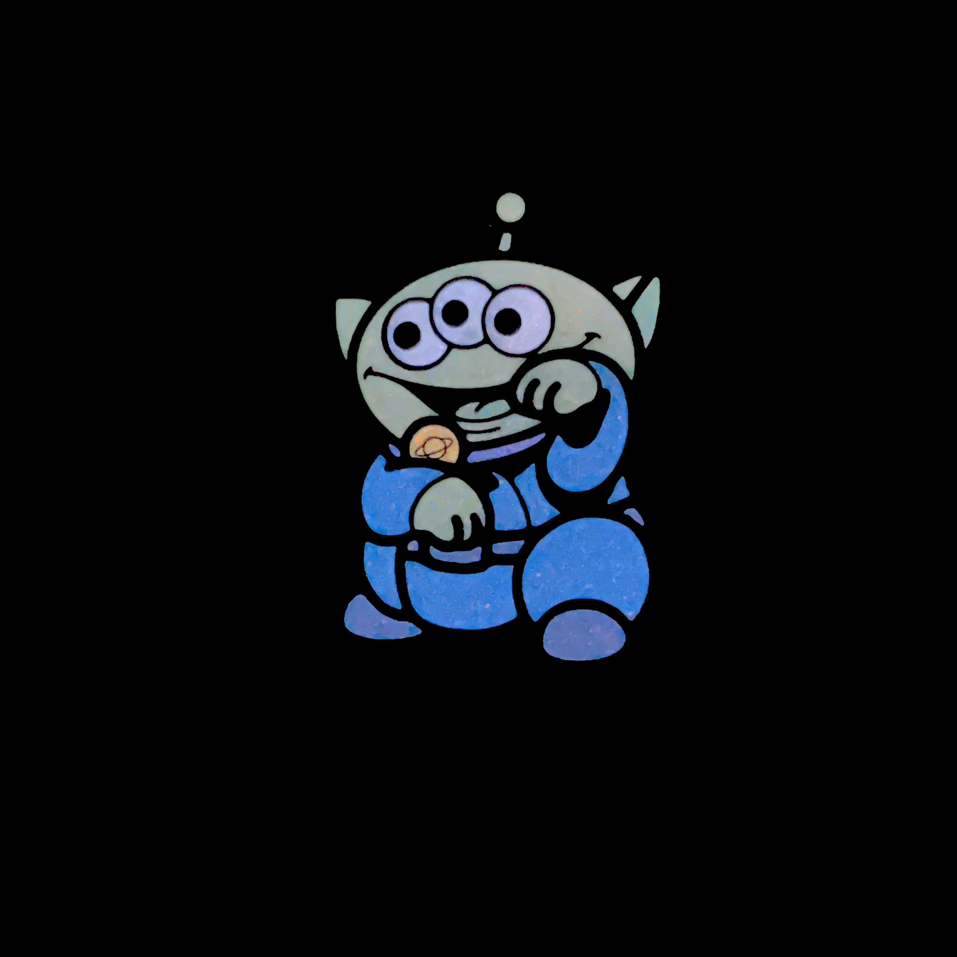 Alien Neko Pin glow inthe dark enamel pin showing a green cartoon alien with 3 eyes wearing a blue outfit in a lucky cat maneko pose.