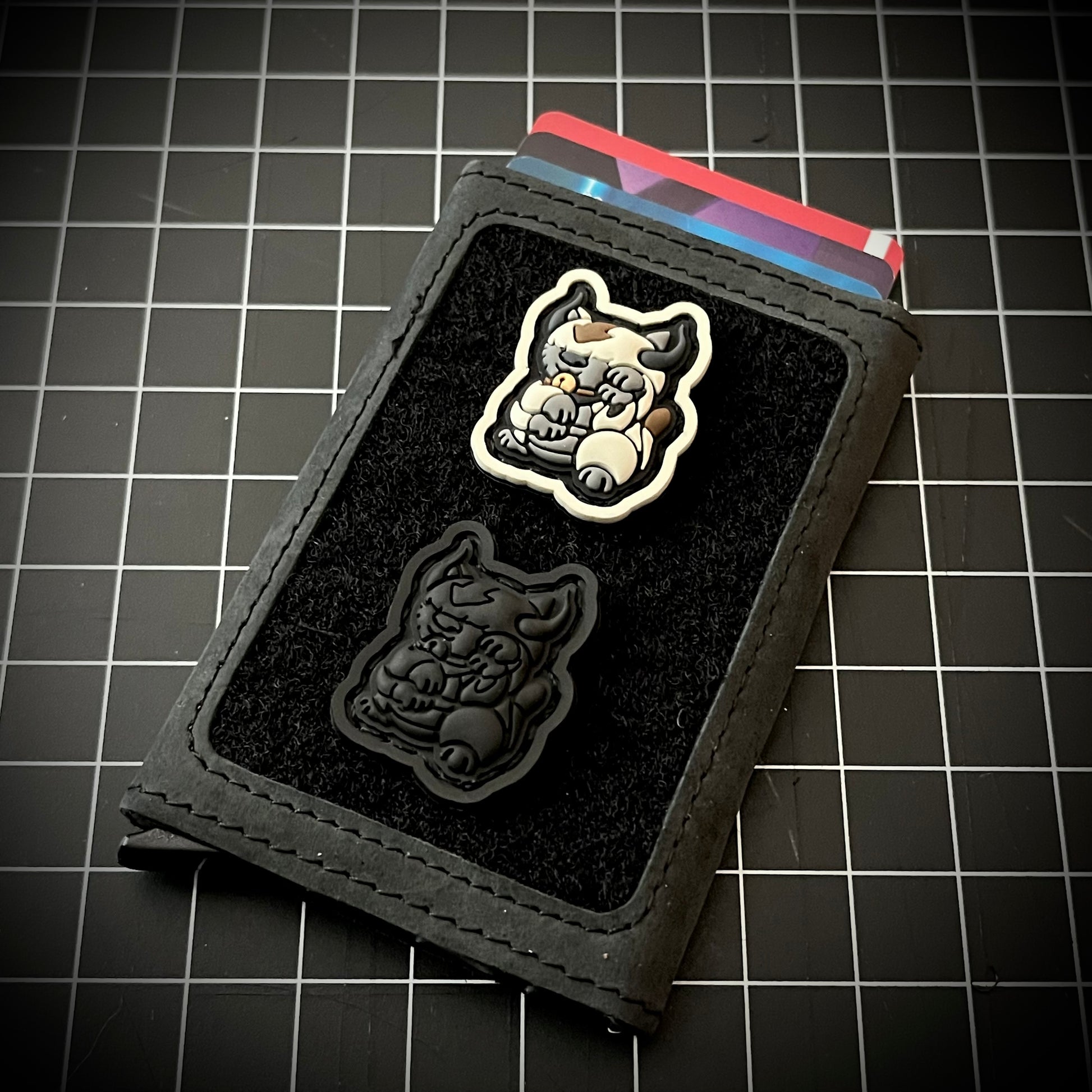 Appa Neko RE and Appa Neko Blackout RE of a bison sitting in a lucky cat maneko pose on a velcro wallet with a grid background.