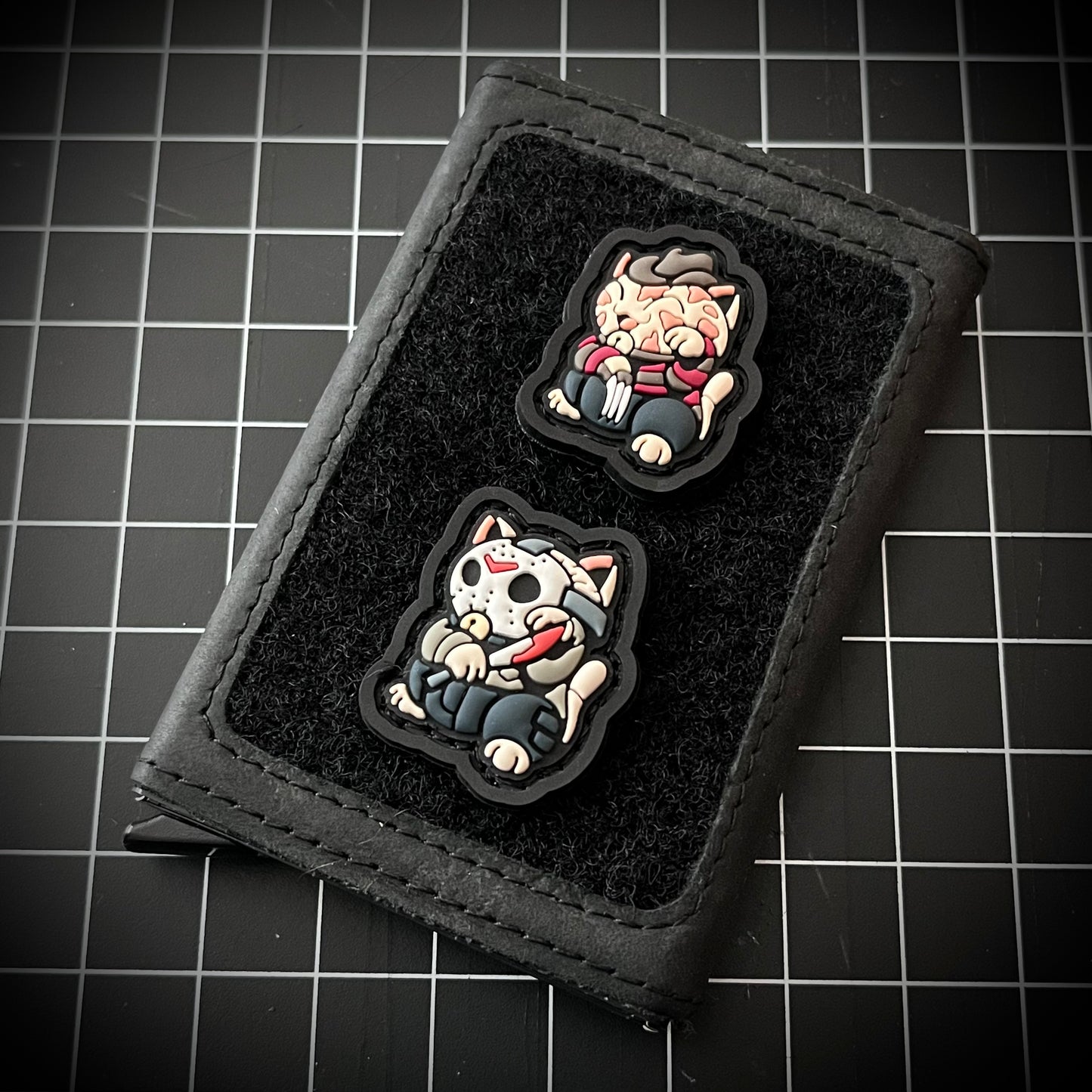 Dream Monster Neko RE and SlasherNeko RE on a velcro wallet and a grid background