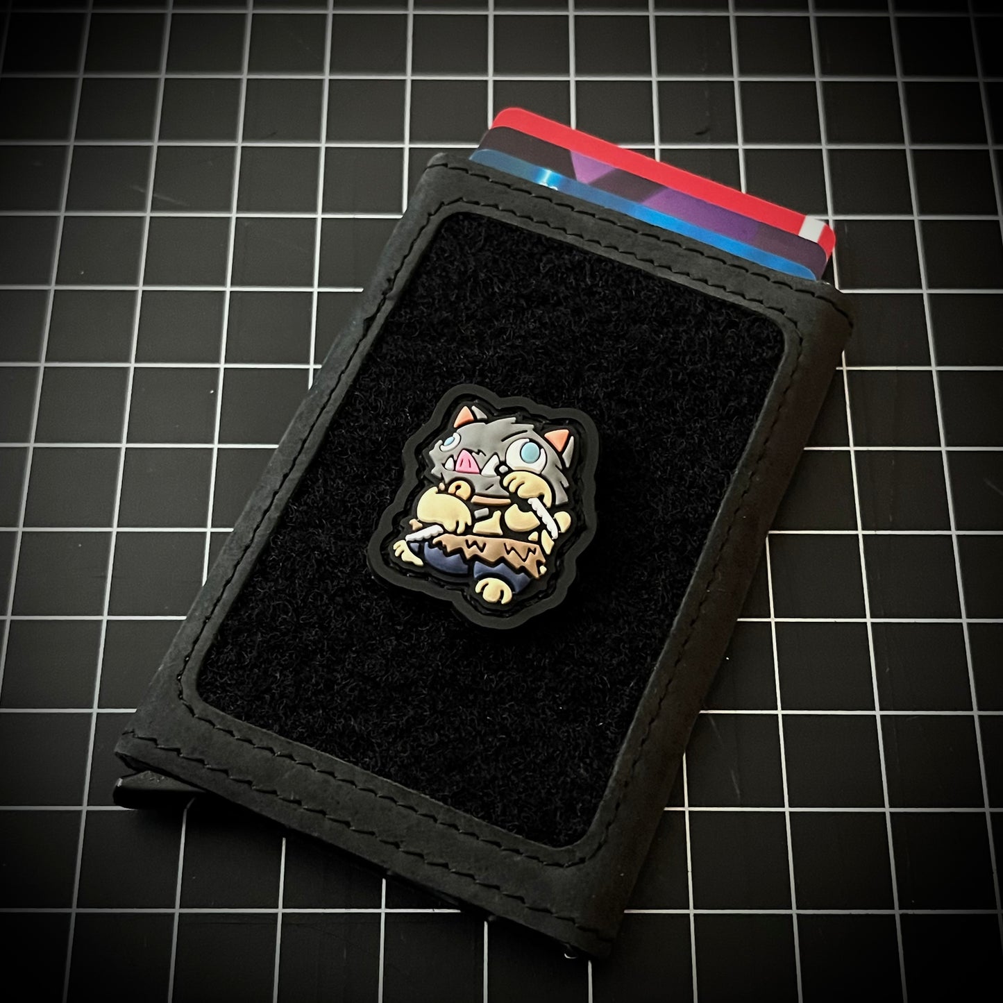 Inosuke Neko RE PVC ranger eye morale patch of demon slayer in a lucky cat maneki-neko pose on a velcro wallet and grid background.