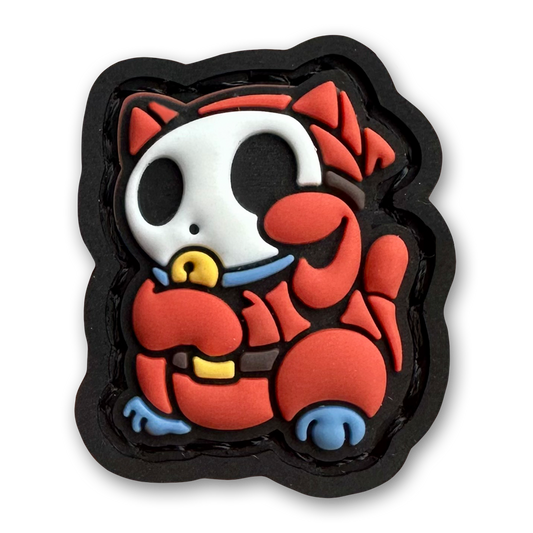 M08 Neko RE PVC ranger eye morale patch of a red cartoon character wearing a white mask sitting in a lucky cat maneki-neko pose.
