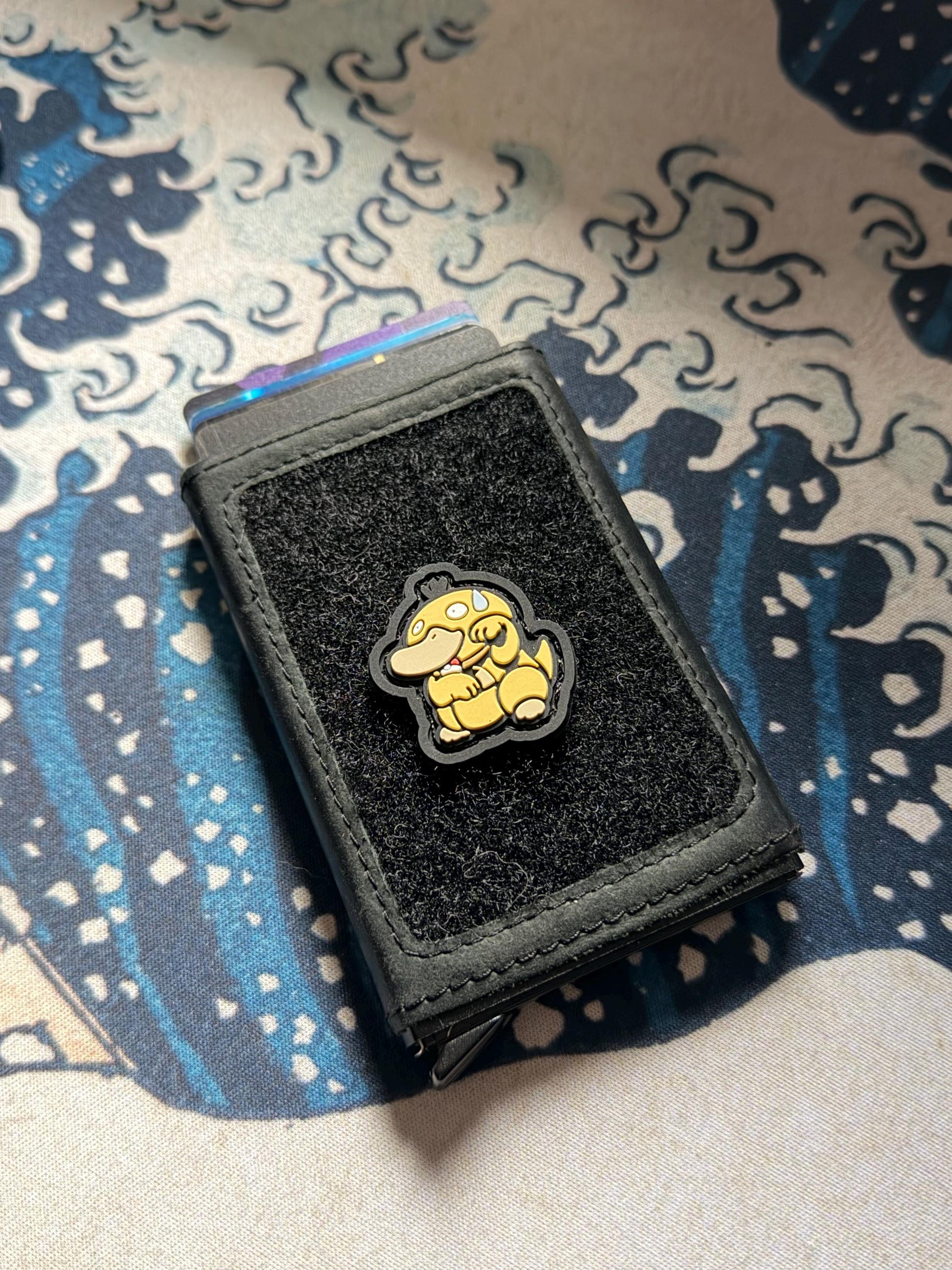 Nervous Duck Neko RE ranger eye morale patch showing a yellow duck with sweat on its head in a lucky cat maneki neko pose on a wallet with a Great Wave background.