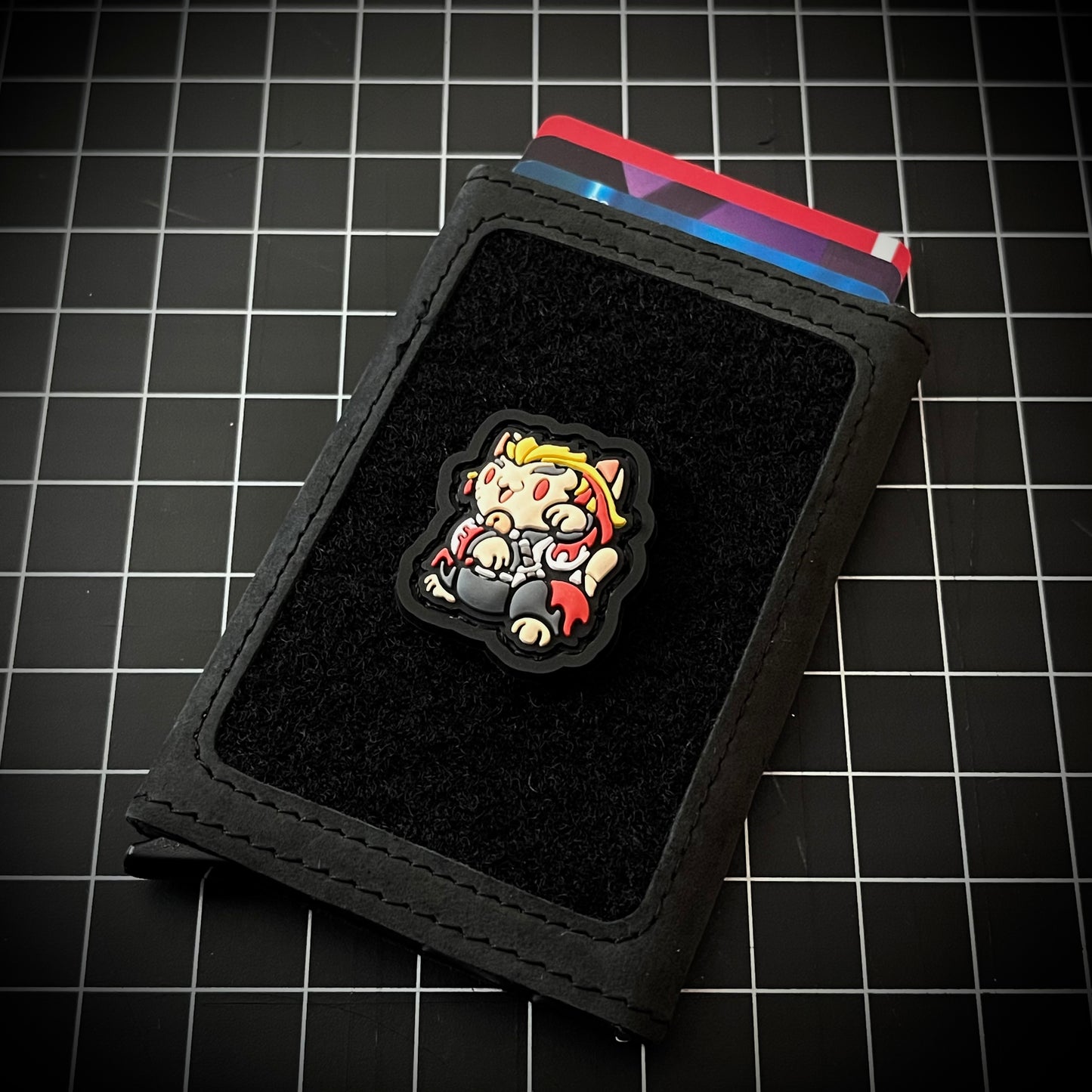 Rengoku Neko RE PVC ranger eye morale patch of a demon slayer anime character in a lucky cat maneki-neko pose on a velcro wallet and grid background.