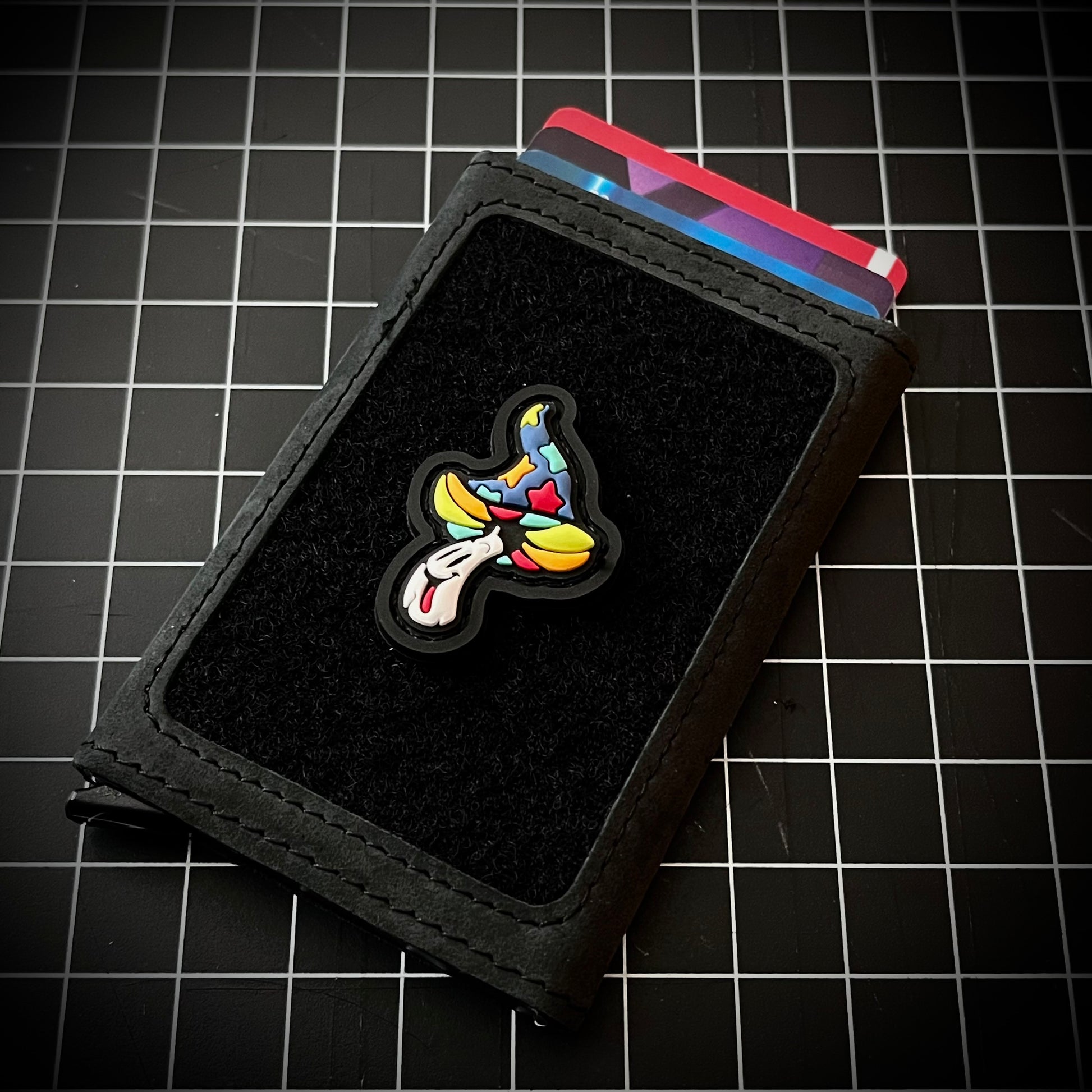 Shroomie RE - Candy PVC ranger eye morale patch of a colorful  mushroom character on a velcro wallet and grid background.