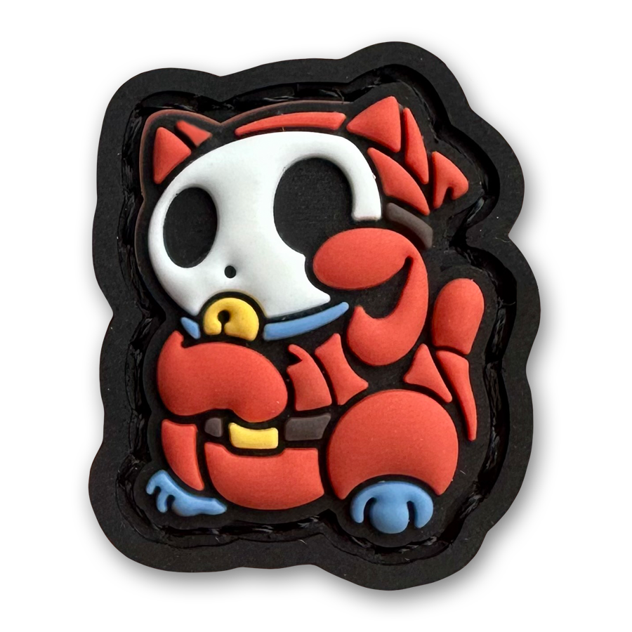 Shy Guy Neko RE PVC ranger eye morale patch of a red cartoon character wearing a white mask sitting in a lucky cat maneki-neko pose.
