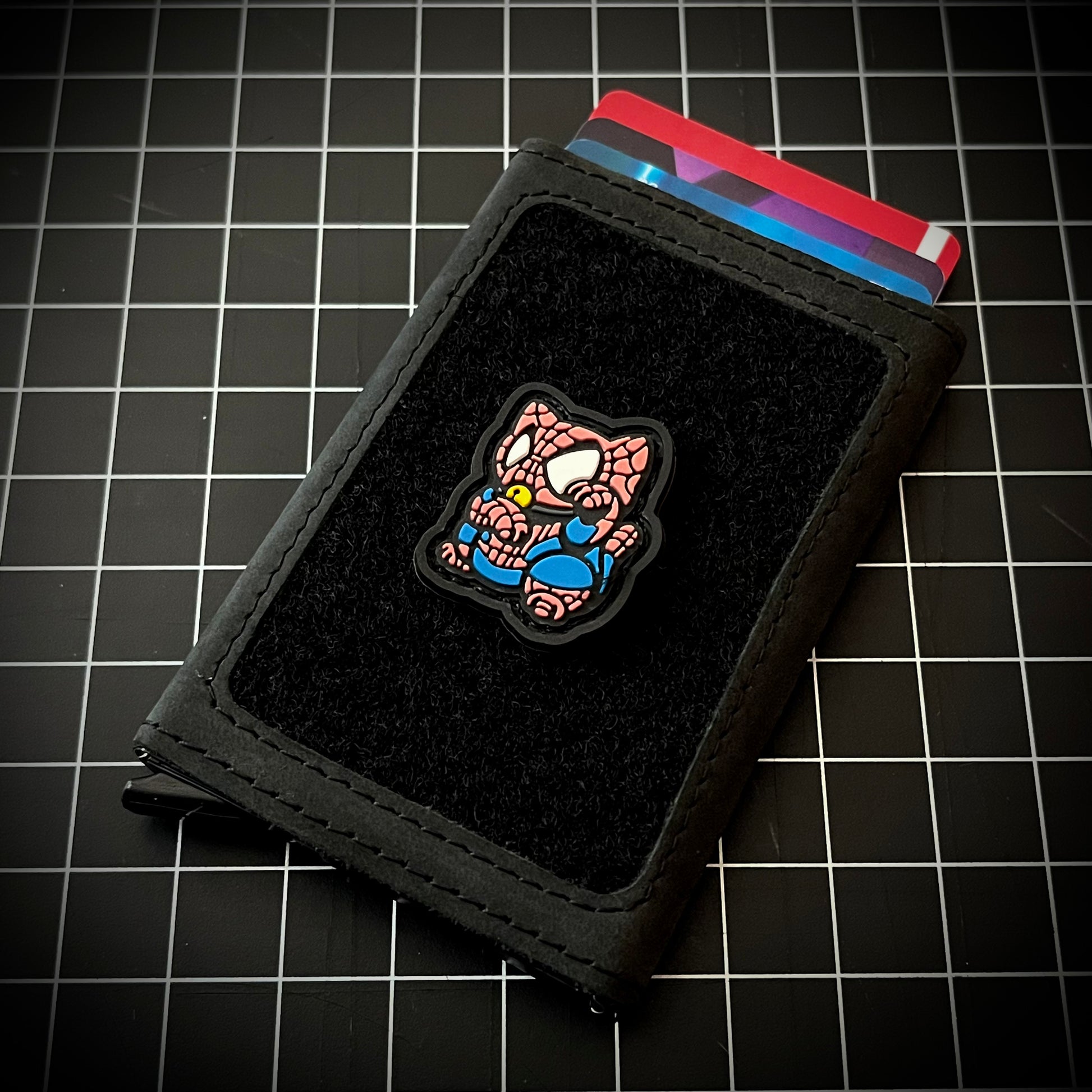 Spider-Man Neko RE PVC ranger eye morale patch of a superhero in a lucky cat maneki-neko pose on a velcro wallet and grid background.