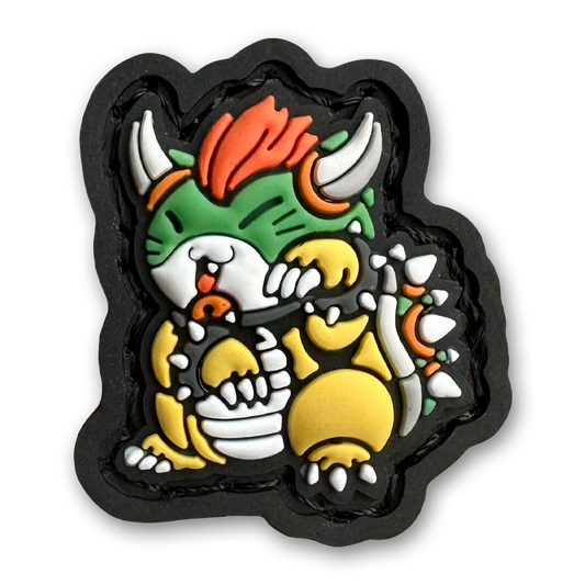 Spiked King Neko RE PVC ranger eye morale patch of a green monster with horns and spiky shell standing in a lucky cat maneki-neko pose.