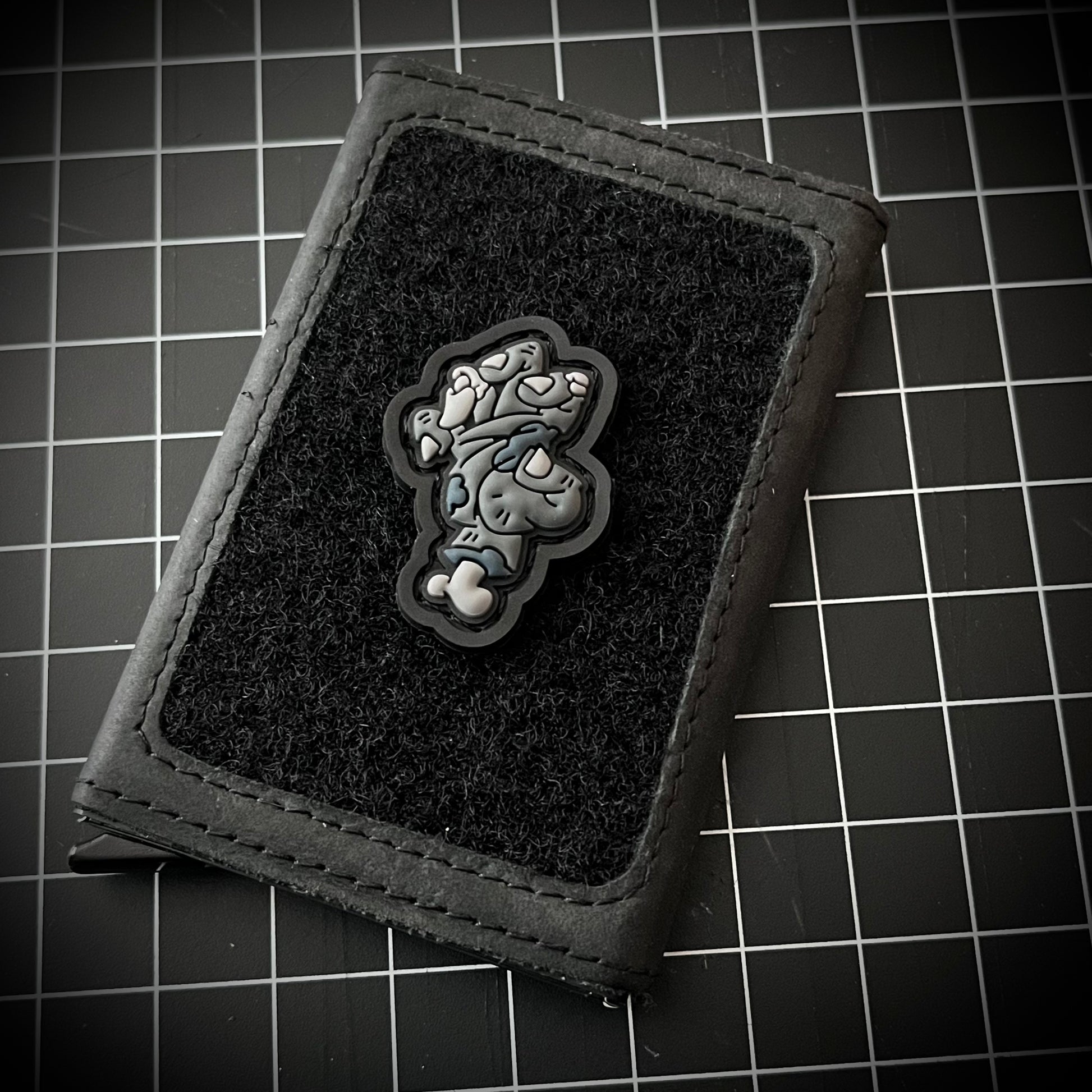 Zombie Hand RE - Gray PVC ranger eye morale patch of a grayscale zombie hand with exposed bones on a velcro wallet and grid background.